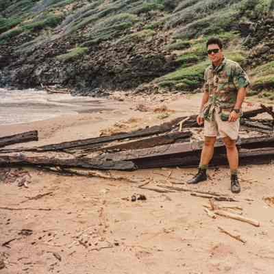 Michael Nāho'opi'i standing next to the remains of the metal railroad ties