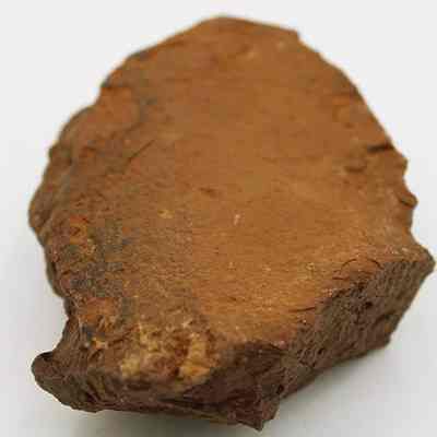 Lengthwise view of a grinding stone: The image depicts a rough, brown grinding stone with a textured surface, likely used for sharpening or grinding tools, placed against a plain background.