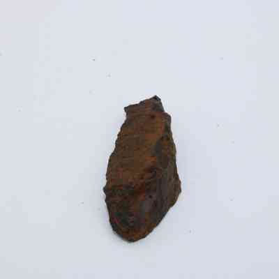 Lengthwise view of basaltic glass: The image shows a piece of basaltic glass with a rough, dark surface and a slightly reddish-brown hue, set against a plain white background.