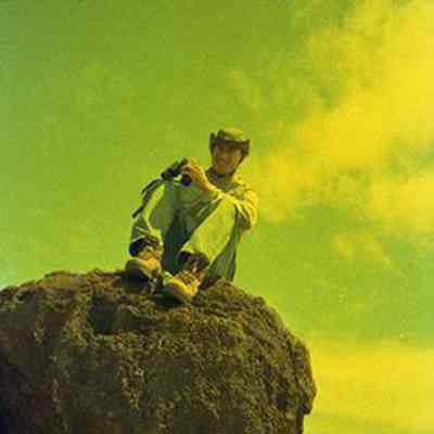 Unidentified man sitting on a pohaku (boulder)
