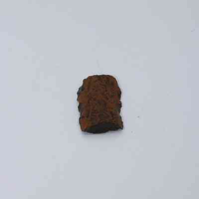 Lengthwise closeup of basaltic glass core: The image shows a piece of basaltic glass core with a rough, textured surface, displaying a mix of brown and black hues.