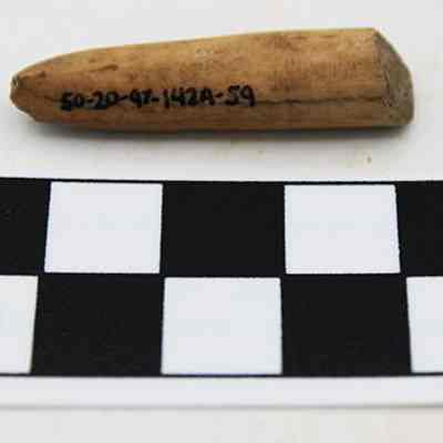 Abrader with scale: The image depicts a small, pointed artifact with writing on it, positioned above a black-and-white scale marked "CM," used for size reference.