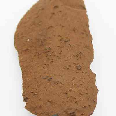 Lengthwise view of rough side of basalt knife (pahi): The image shows a blade-like object with a brown, heavily corroded surface, suggesting it may be an ancient knife (pahi) made from basalt.