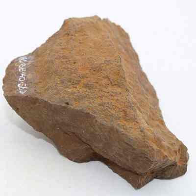 Whetstone (hoana) fragment: The image shows a rough, brown whetstone (hoana) fragment with irregular edges, displaying a natural, weathered texture, used traditionally for sharpening blades.