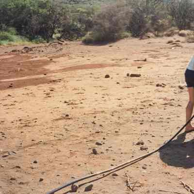 Two men uncoiling a black hose