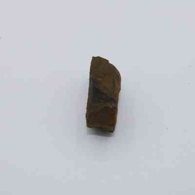 Edge of basaltic glass piece: The image shows a piece of basaltic glass with a rough, dark surface, centered against a plain white background.