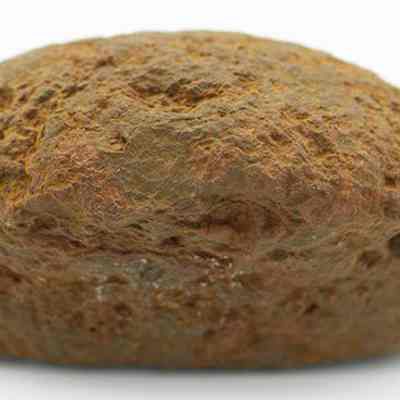 Closeup profile of breadloaf sinker: The image shows a single, bread-loaf shaped brown rock with a rough, textured surface, appearing weathered and slightly reddish in color, against a plain white background.