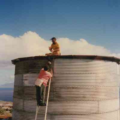Two people working on water tank