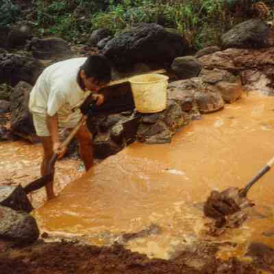Men digging mud out of stream