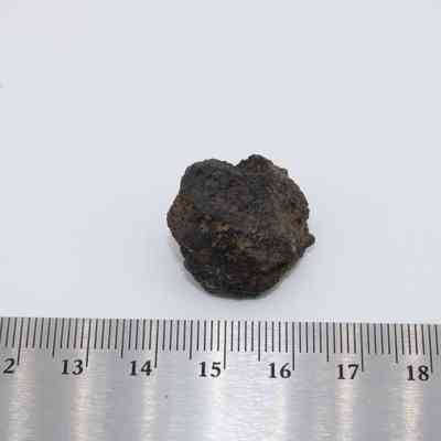 Closeup of basaltic glass core with ruler: The image shows a small, irregularly shaped basaltic glass core next to a ruler for scale.