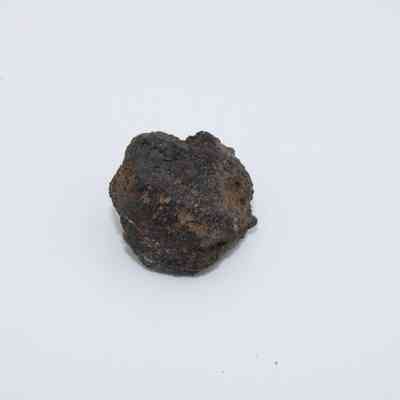 Close up of basaltic glass core: The image features a single piece of basaltic glass core against a plain white background, highlighting its rough texture.