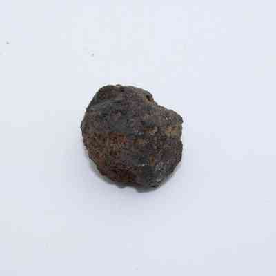Closeup of basaltic glass core: The image shows a rugged, dark basaltic glass core with a rough, irregular surface texture on a plain white background.