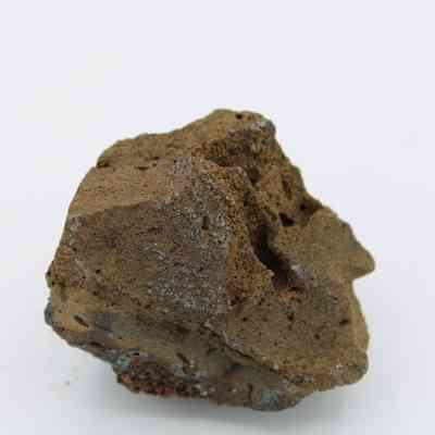 Closeup of basaltic glass core: The image depicts a rough piece of basaltic glass with a textured surface and a combination of earthy and metallic tones.