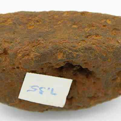 Bottom of breadloaf sinker with visible alternate id number: The image shows the underside of a rock shaped like a bread loaf with "7.35" handwritten on a small white label.