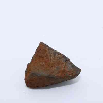Closeup of basaltic glass piece: The image shows a rough, triangular piece of basaltic glass, showcasing its dark, volcanic texture with reddish-brown patches on its surface.
