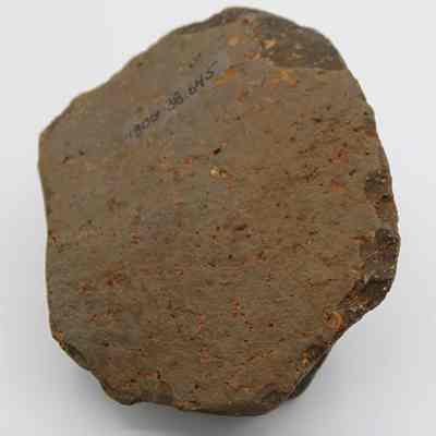 Base of core/scraper with visible alternate id number: The image shows a roughly shaped, brownish stone artifact with an identification number on its surface, placed against a plain white background near a ruler for scale.