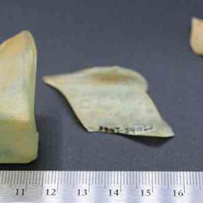 Glass bottle fragments with ruler: Four bottle fragments are laid out on a black surface, with a ruler for scale.