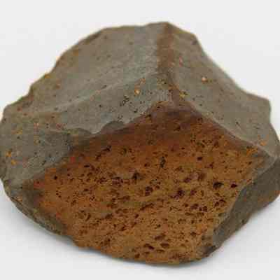 Basalt core/scraper: The image shows a roughly shaped rock or stone with a textured, uneven surface, displaying dark gray and brown hues.