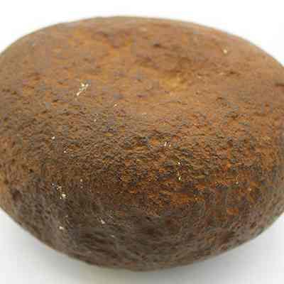 Closeup profile of a basalt hammerstone: The image features a hammerstone, possibly a pre-Western contact tool made from a roughly spherical stone with a weathered and textured surface.