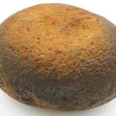 Basalt hammerstone: The image shows a rounded, weathered hammerstone, likely used in ancient stone-working, with a textured surface and a natural indentation, indicating prolonged use