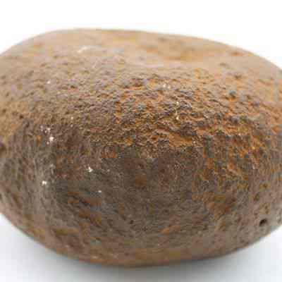 Profile of a hammerstone: The image shows an ancient hammerstone, characterized by its rounded shape and textured, weathered surface, primarily used for tool-making.