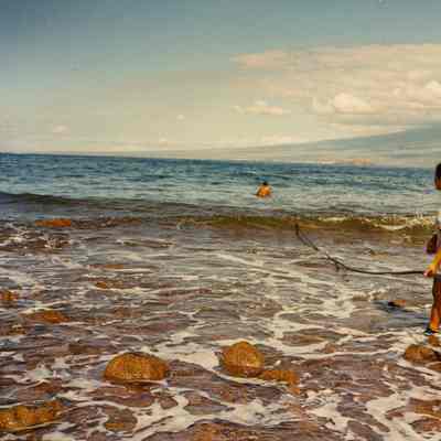 Two people running hose into the ocean
