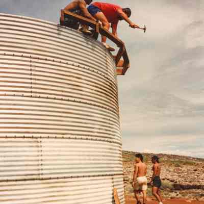 Man hammering on frame at the top of a water catchment structure