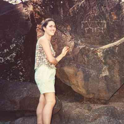 Woman posing in front of kiʻi pōhaku (petroglyph)