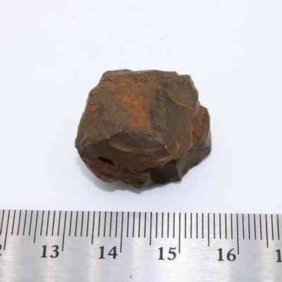 Closeup of basaltic glass core with ruler: A small, dark basaltic glass core sits beside a ruler, measuring about 2.5 centimeters in length.