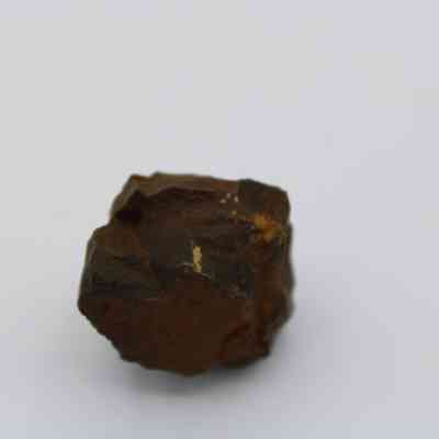 Closeup of basaltic glass core: The image shows a roughly shaped basaltic glass core, exhibiting a dark brown to black surface with irregular, textured edges.
