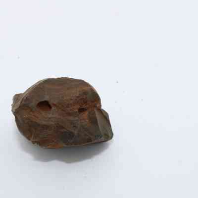 Closeup of basaltic glass core: The image shows a piece of basaltic glass core with a rough, uneven surface against a plain background.
