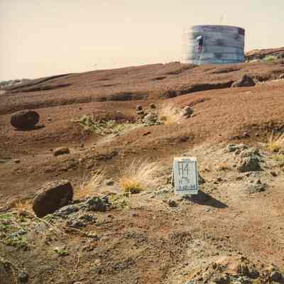 Hardpan terrain with sign and water catchment