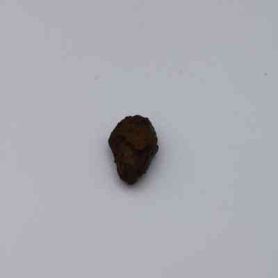 Triangular shaped basaltic glass core: The image displays a small, irregularly shaped piece of basaltic glass core, exhibiting a dark, rough surface against a plain background.