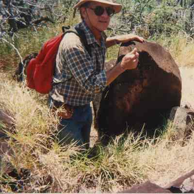 Unidentified man near a rock with petroglyphs