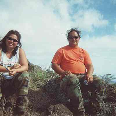 Two people sitting on pohaku (rocks)