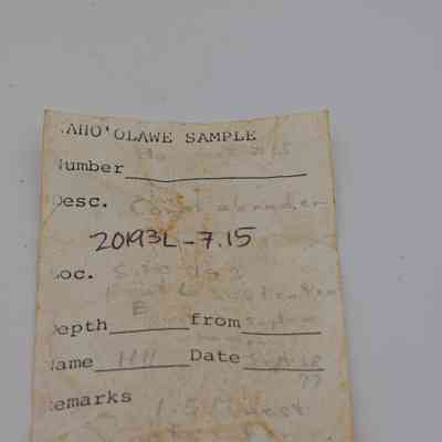 Artifact slip for an coral abrader: The image displays a weathered artifact slip labeled "KAHO'OLAWE SAMPLE" with details like "Desc." and "Loc." handwritten on it.