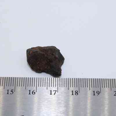 Basaltic glass core above ruler: A small piece of basaltic glass lies on a white surface, adjacent to a metallic ruler indicating its size.