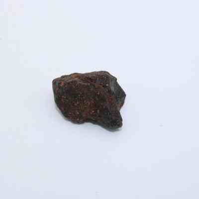 Closeup of basaltic glass core: The image shows a small, dark basaltic glass core with a rough texture, set against a plain white background.