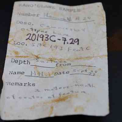 Artifact slip for cowrie shell lure (lu he'e): The artifact slip is a slightly worn paper labeled "Kaho‘olawe Sample," detailing its specific number and location data.