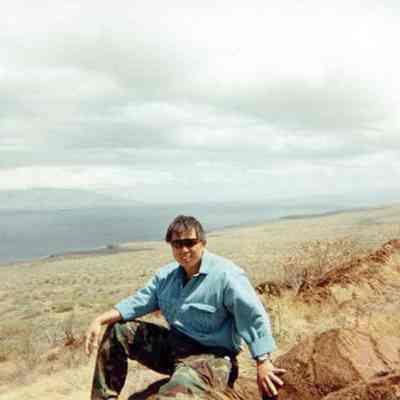 Derek Chow sitting on a pohaku (boulder)