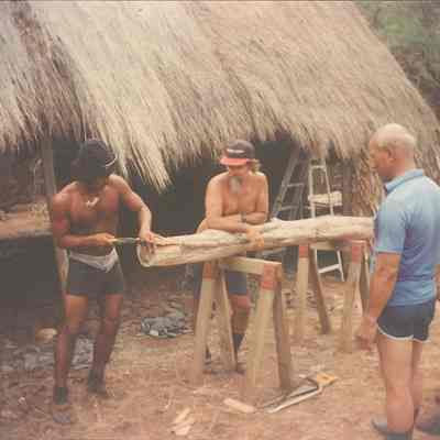 Four unidentified men working on log