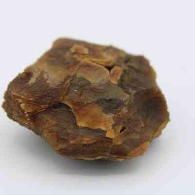 Closeup of agate core: The image shows a brown and orange agate slice with a rough texture, showcasing its layered, natural patterns against a plain background.