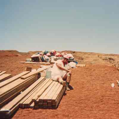 Person sitting on stack of lumber