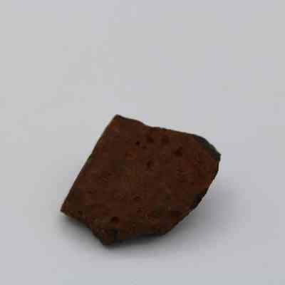 Closeup of basaltic glass core: The image depicts a small, irregularly shaped basaltic glass core with a rough, textured surface.