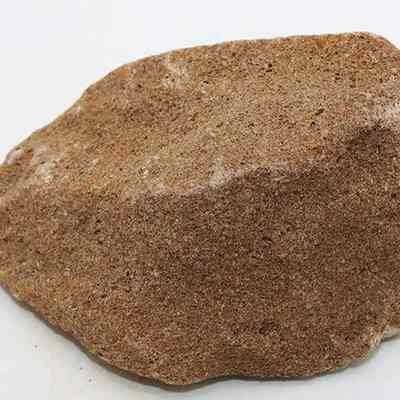 Closeup of pumice file: The image shows a close-up of a brown pumice stone with a rough texture.