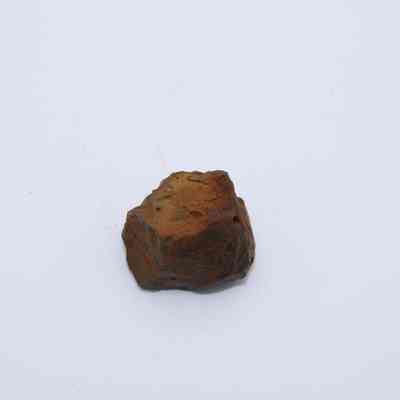 Closeup of basaltic glass core: The image shows a rough, irregular piece of brown basaltic glass core, resting on a plain white background.