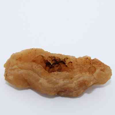 Closeup of a calcite piece: The image shows a brownish, rough-textured calcite formation with intricate surface patterns against a plain white background.