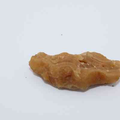 Profile of a calcite piece: A rough, brown calcite mineral specimen is positioned on a plain white background, showcasing its natural textures and earthy tones.