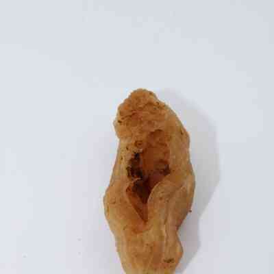 Lengthwise view of calcite piece: A brown calcite specimen with a rough, textured surface and an irregular shape is displayed against a plain white background.