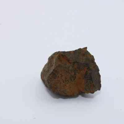 Closeup of basaltic glass: The image shows a piece of basaltic glass with rugged surfaces and a dark, earthy appearance on a white background.